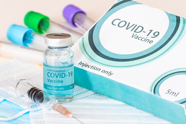 Medische fles, flesjes, spuiten en gezichtsmasker. coronavirusvaccin - nieuw vaccin tegen coronavirus sars-cov-2 op laboratoriumtafel. vaccinatiesessie en verbetering van de immuniteit.