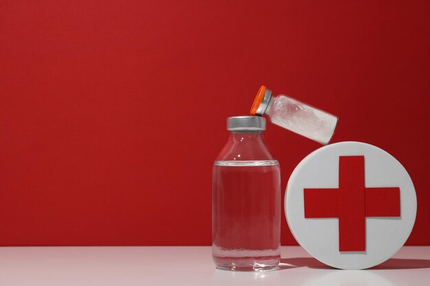Medische glazen flessen en doos met rood kruis op rood achtergrond ruimte voor tekst