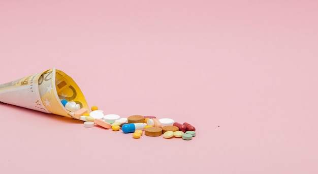 Medische pillen en tabletten in eurobankbiljettengeld als symbool van de kosten van de gezondheidszorg
