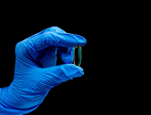 Medische pillen op geïsoleerde zwarte achtergrond met reflectie in de hand