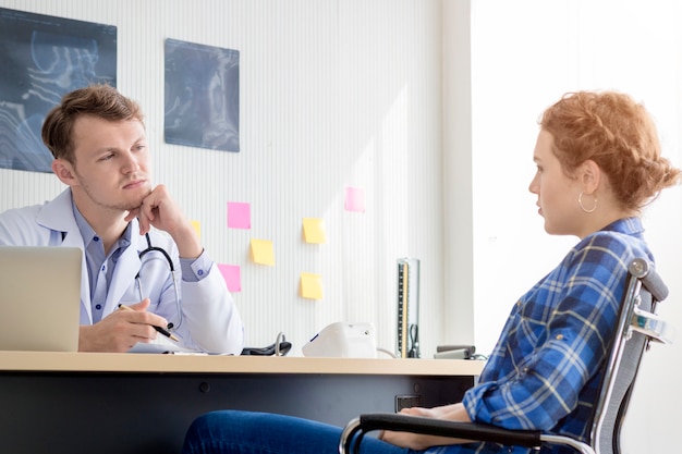 Medische professionals man geruststellend en praten met jonge vrouw stress-patiënt.