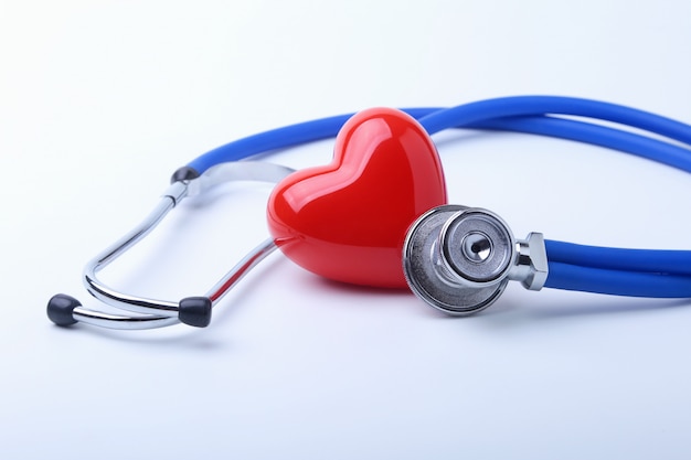 Medische stethoscoop en rood hart dat op wit wordt geïsoleerd.