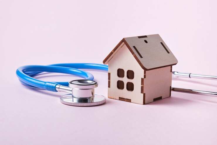 Medische stethoscoop en speelgoed huis op een roze oppervlak met kopie ruimte