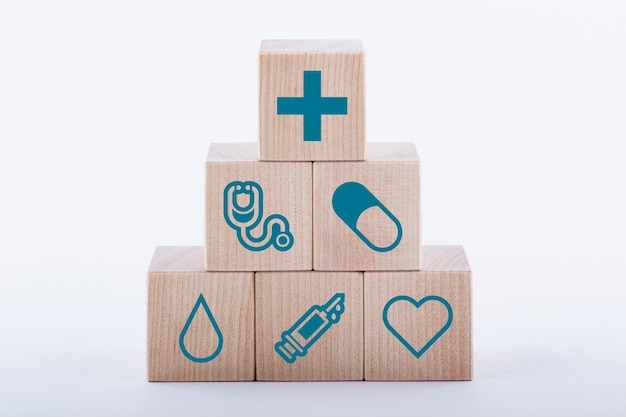 Medische symbolen op houten blokken gestapeld in een piramide op witte achtergrond Geneeskunde concept