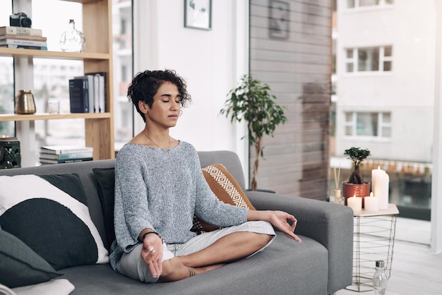 Meditatie leert je dat het leven geen pijn mag doen Shot van een aantrekkelijke jonge vrouw die thuis op een sofa mediteert