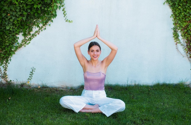 Meditatie yoga vrouw in het voorjaarspark vrouw die stretching doet buiten op groen gras fit meisje in sportkleding die ochtend yoga doet