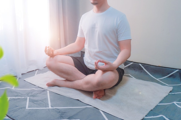 家で一人で瞑想する家の自由と静けさの概念で瞑想する若い男のショット