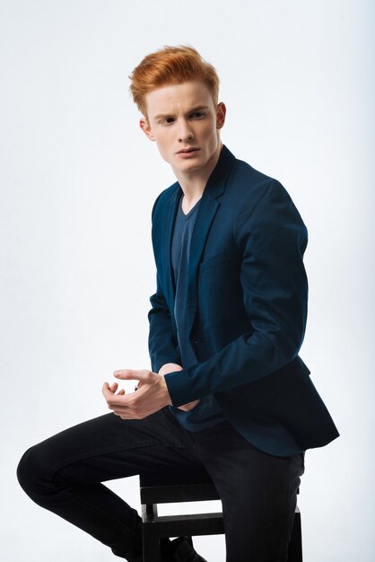 Meditation. Attractive serious red-haired young man wearing a black jacket and looking in the distance and touching his wrist