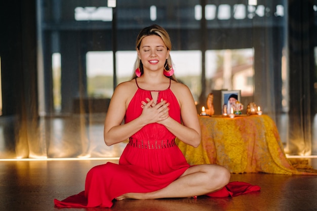 Meditazione e concentrazione una donna con un vestito rosso seduta sul pavimento sta praticando la medicina all'interno calma e relax