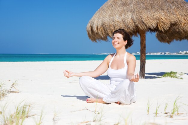 медитация счастливой женщины в позе лотоса на пляже