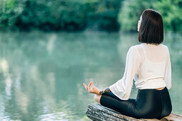 Photo meditation in nature woman sitting in lotus position and meditating by the lake