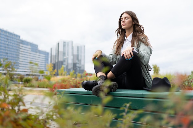 Meditation of an office employee on a park bench in a yoga\
position against the backdrop of office