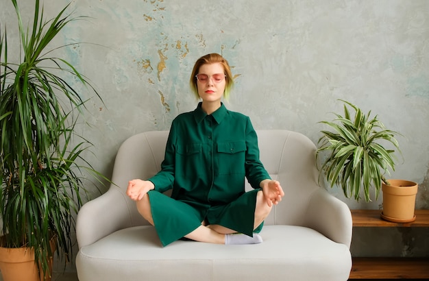 Meditation with a phone in his hands, deep breathing. Mobile meditation application. Concept young woman sitizen relaxes and meditates in a modern interior. Millennial.