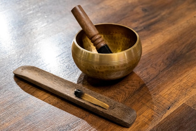 Meditazione con campana tibetana e bastone aromatico bruciante su sfondo di legno