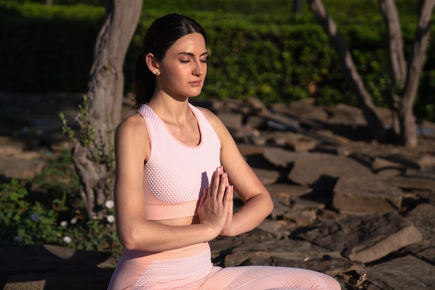 Mediteert in de natuur. Een meisje houdt zich bezig met yoga op straat, in een roze trainingspak doet verschillende oefeningen en yogahoudingen