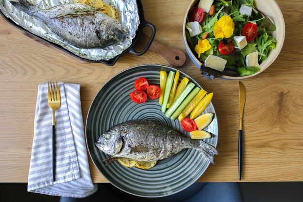 Mediterrane keuken op tafelDorada uit de oven met salade en kaasKaasplateau met noten en saladeGoede voeding op tafelGroenten met gebakken vis Kant-en-klare visDorado grill