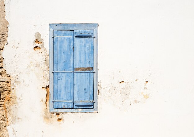 Mediterrane stijl oud venster. Blauw op lichte muur met gesloten luiken.