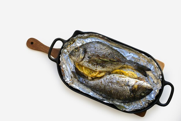 Mediterranean diet Baked gilthead with lemon and herbs Baked Dorada on a pan Dorada grill Proper nutrition Cooked fish on a white plate with copywriting spaceDorada cooked in the ovenBaked fish