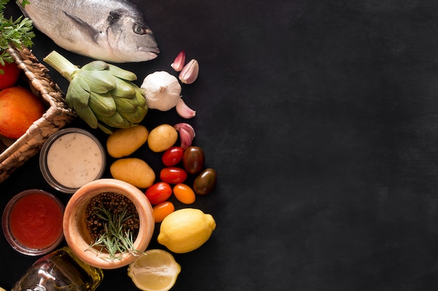 Mediterranean fish - dorado and vegetables on the chalkboard. top view