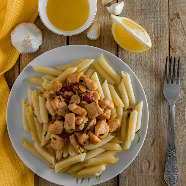 Foto cucina mediterranea: pasta di penne e pollo delizioso in salsa cremosa su un tovagliolo giallo. vista dall'alto