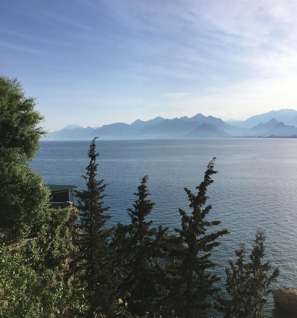 淡い霞の中に穏やかな海と高い山のシルエットを持つ、柔らかな色の地中海の風景