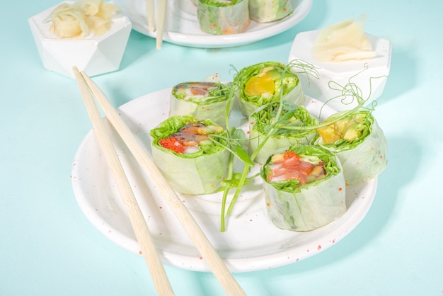 Mediterranean, nordic and keto diet concept. Sushi without rice, diet food with seafood, vegetables. Trendy asian sushi-styled Spring rolls on blue modern background