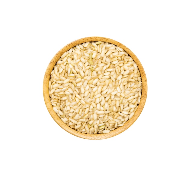 Medium grained rice heap in wooden brown bowl isolated on white background, top view. Unpolished organic brown rice grain with germ