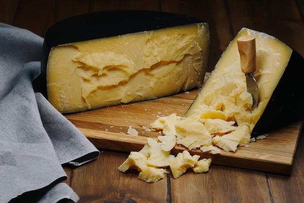 Medium hard cheese head parmesan on wooden board with cheese parmesan knifes