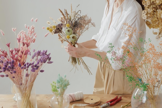 Medium height woman working with dried flowers assemble composition decor and floristry concept