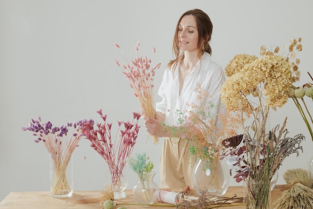 Женщина среднего роста, работающая с сухоцветами, собирает композицию декора и концепцию флористики