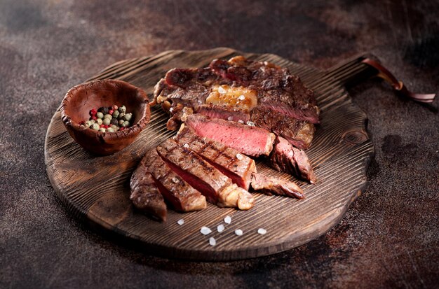 Medium rare grilled beef steak ribeye on a brown rusty background