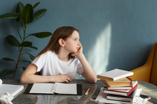 Foto ragazza annoiata del colpo medio che si siede alla scrivania