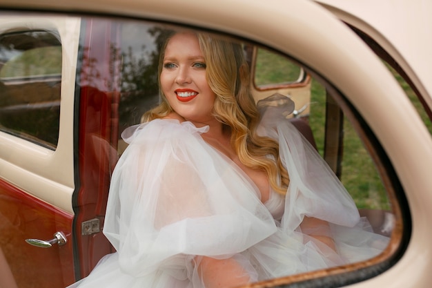 Foto sposa del colpo medio che posa in auto d'epoca