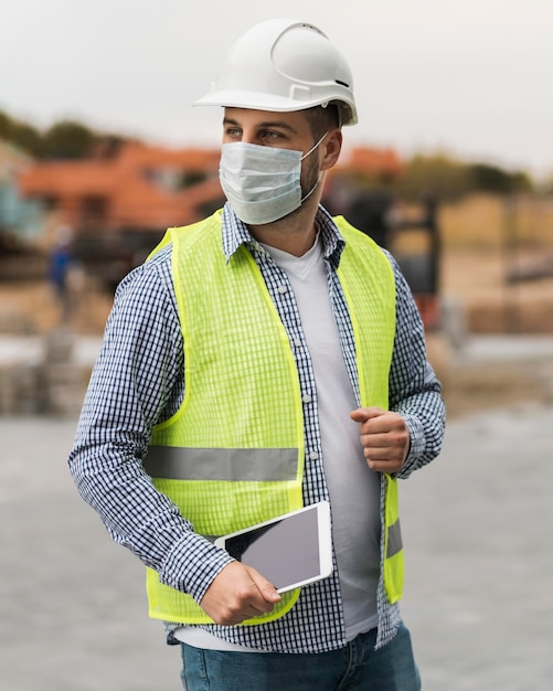 Foto uomo del costruttore del colpo medio che indossa maschera medica