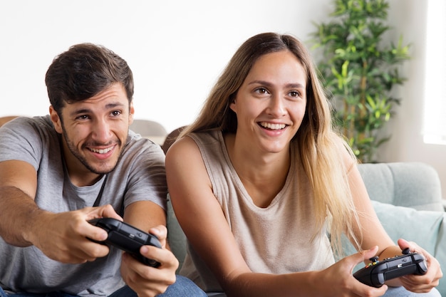 Medium shot couple with controllers at home