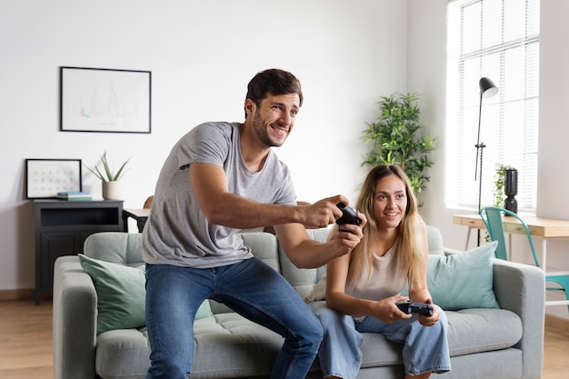 Medium shot couple with controllers indoors