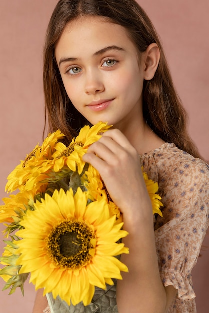 Photo medium shot cute girl holding sunflowers