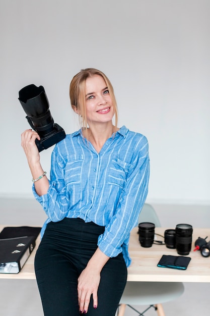 Colpo medio della giovane donna sveglia che tiene una macchina fotografica