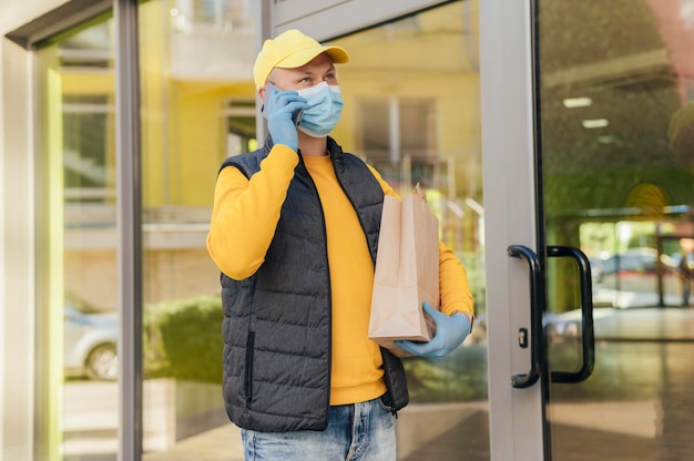 Uomo di consegna del colpo medio che tiene il sacchetto di carta