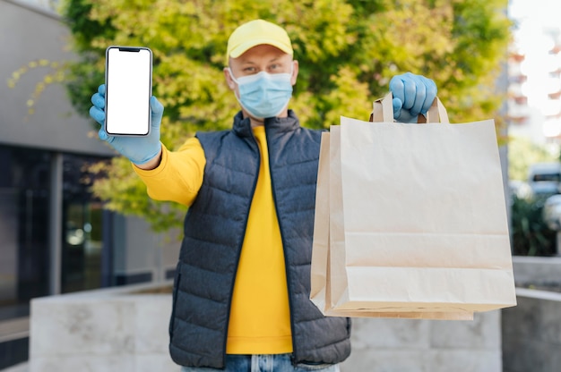 Photo medium shot delivery man holding smartphone