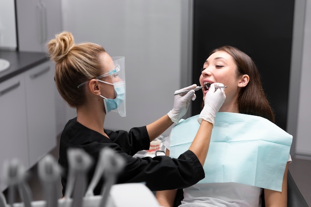 Dentista a colpo medio che controlla il paziente