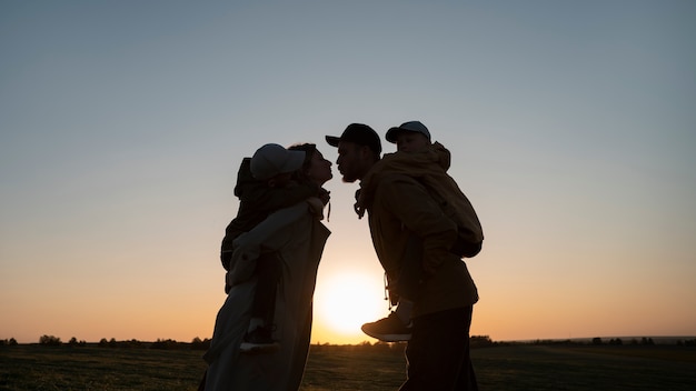 Foto siluetta della famiglia del colpo medio che si diverte al tramonto