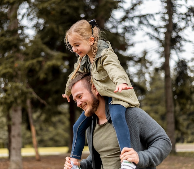 Medium shot father carrying girl on shoulders