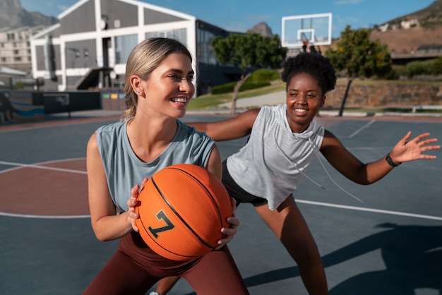 Photo medium shot female friends playing basketball