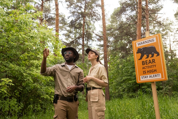 Medium shot forest wardens near warning sign