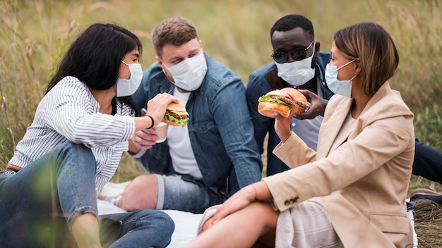 Foto amici di tiro medio con hamburger e maschere