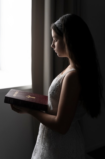 Medium shot girl holding bible