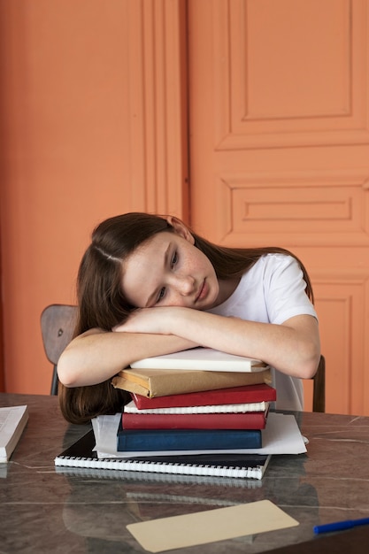 medium shot girl holding head on books