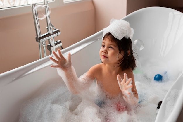 Foto ragazza del tiro medio che gioca nella vasca da bagno