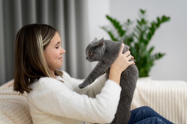 Foto ragazza di tiro medio che gioca con il gatto